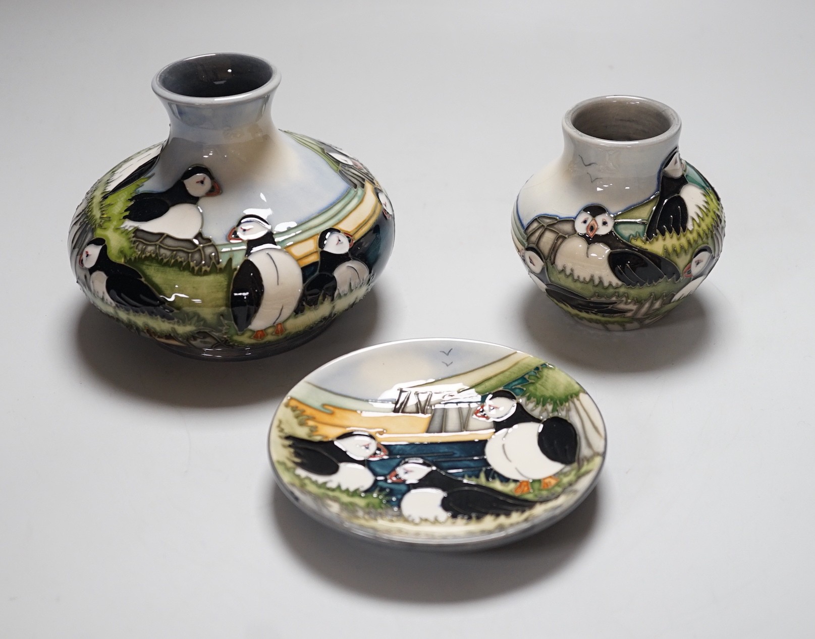Three boxed Moorcroft ‘Puffin’ ceramics: a squat vase, a smaller vase and a dish, squat vase 11cms high
